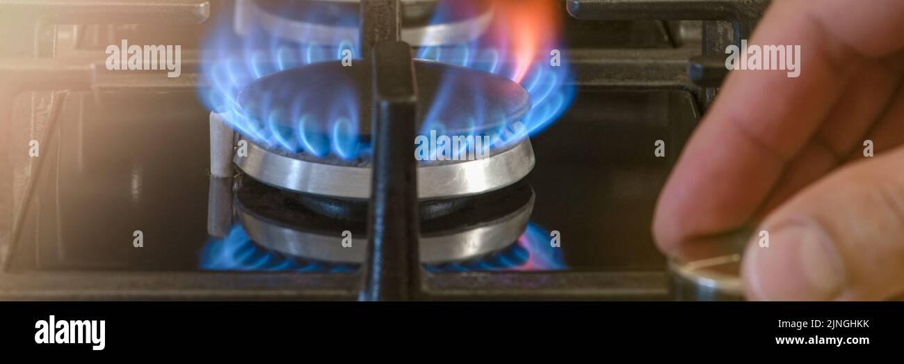 Die Kosten für Gas für den häuslichen Bedarf. Die Hand entschrauben den Gasbrenner in der Küche. Die Verwendung von Gas als Heizenergie im Winter, während der kalten Jahreszeit. Stockfoto