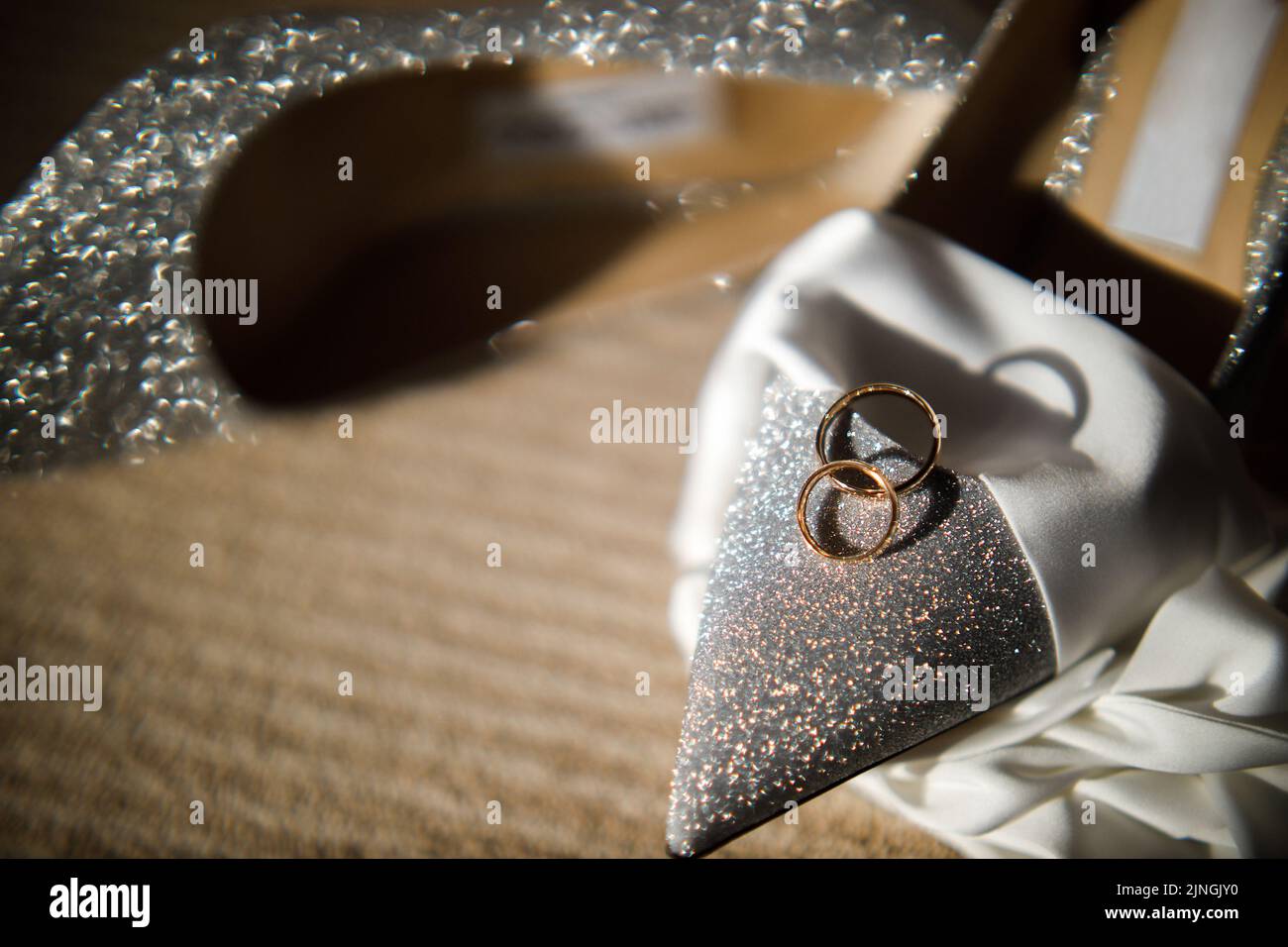 Zwei goldene Ringe liegen auf Hochzeitsschuhen. Stockfoto