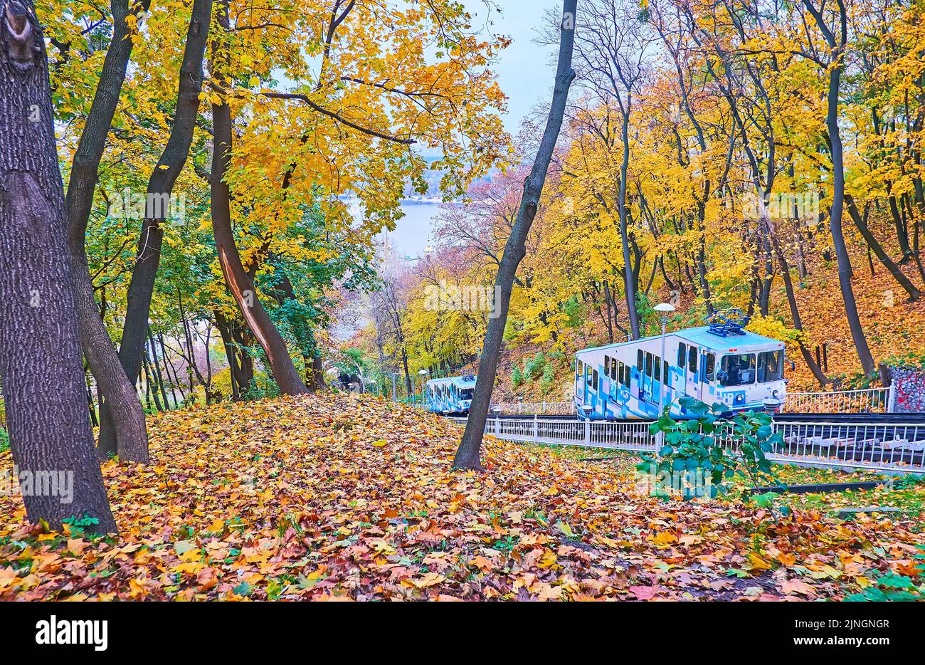 Der malerische Herbstpark des Sankt-Volodymyr-Hügels mit leuchtend gelben und roten Bäumen und Wagen der Kiewer Standseilbahn verbindet die obere und untere Stadt Ukrai Stockfoto