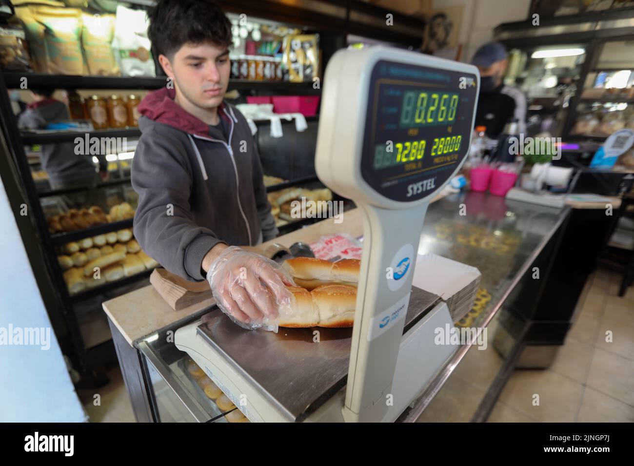Buenos Aires, Argentinien. 10. August 2022. Ein junger Verkäufer wiegt Brötchen in einem Geschäft. Die Preise stiegen im Juli um 71 Prozent gegenüber dem Vorjahr. Die nationale Währung, der Peso, nimmt gegenüber dem US-Dollar weiter ab, und der Schuldenberg wächst weiter. (To dpa 'Inflationsrate in Argentinien steigt auf 71 Prozent') Kredit: Claudio Santisteban/dpa/Alamy Live News Stockfoto