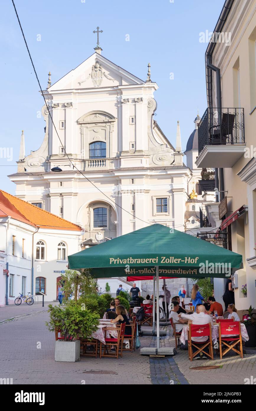 Vilnius Altstadt Straßenszene mit der Kirche St. Theresa und Menschen in einem Café; Vilnius, Lithuania Travel, Lithuania Europe Stockfoto