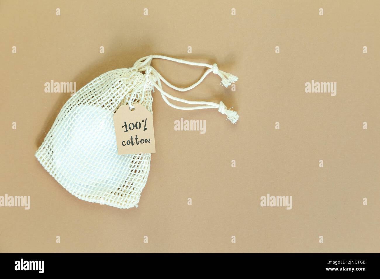 Canvas-Tasche mit Kordelzug und Label, kleine umweltfreundliche Tasche aus Naturbaumwolle auf beigem Hintergrund. Flach liegend, Draufsicht. Stockfoto