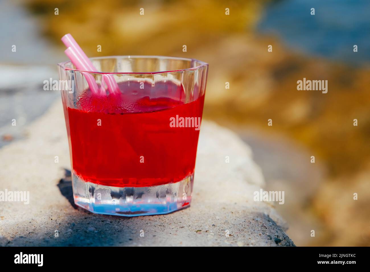 Roter Cocktail in einem Glas, der auf einem Holztisch im Strandcafé steht. Stockfoto