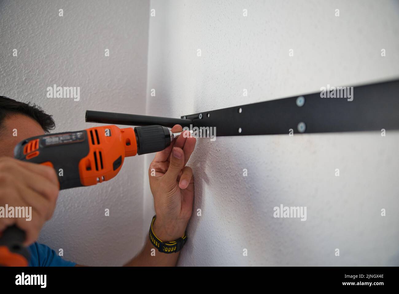 Zimmermann arbeitet sorgfältig, Mann bohrt eine Wand. Arbeiten zu Hause. Stockfoto