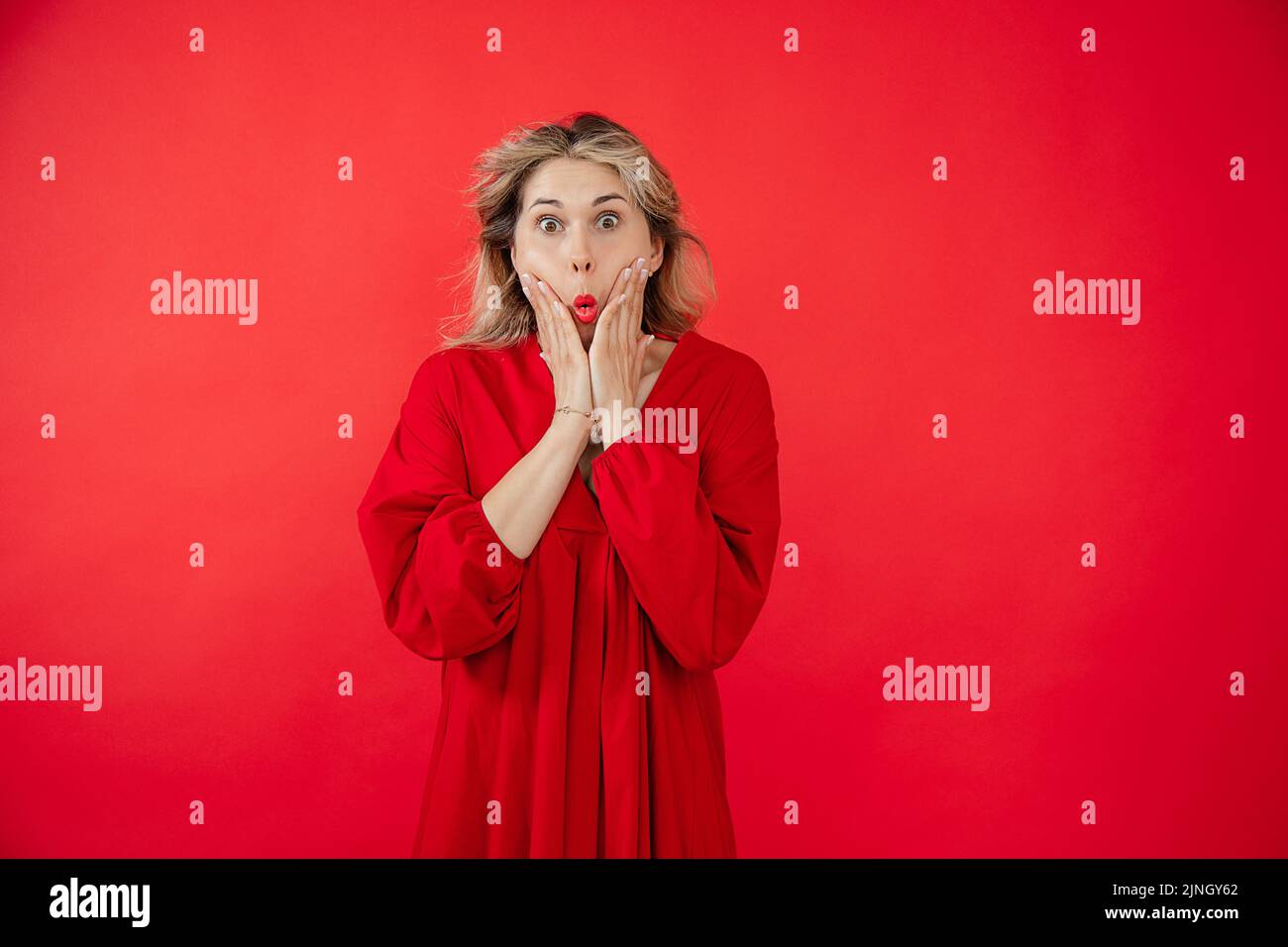 Portrait von wunderschönen jungen Frau in leuchtend roten Kleid fragen und prall Augen isoliert auf rotem Hintergrund. Wow-Effekt, tolles Ergebnis, überraschend mit Stockfoto