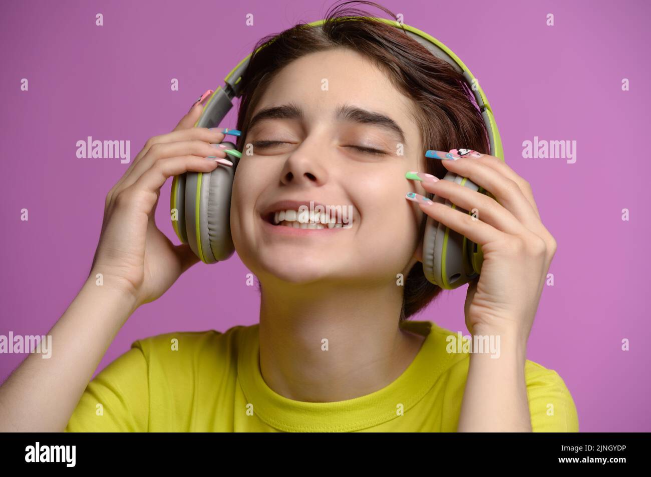 Nette junge Brünette mit Spaß Musik hören mit kabellosen Kopfhörern Stockfoto