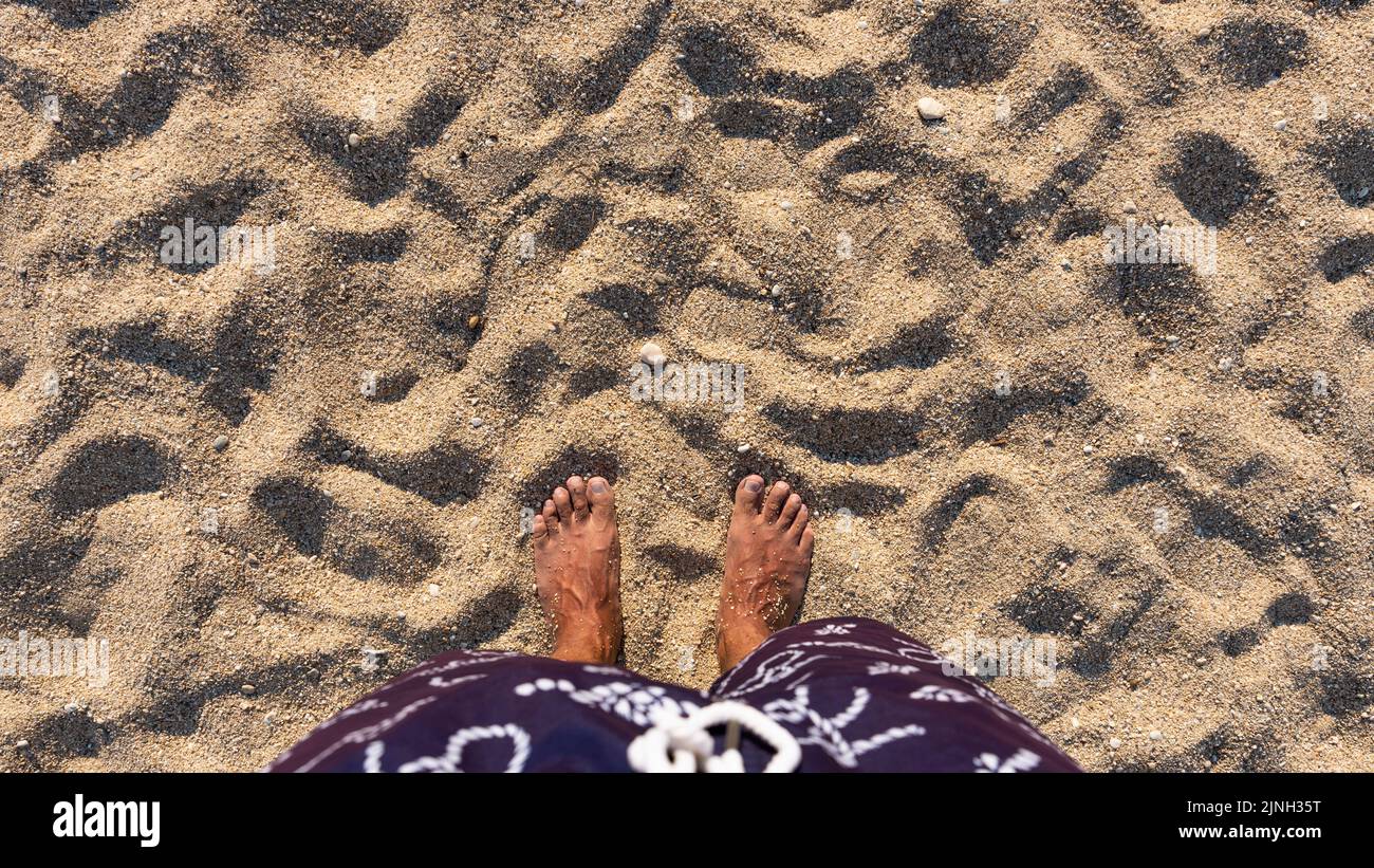 Barfuß am Strand stehen. Füße von Menschen am Sandstrand. Draufsicht. Leerzeichen für Text oder Logo Stockfoto