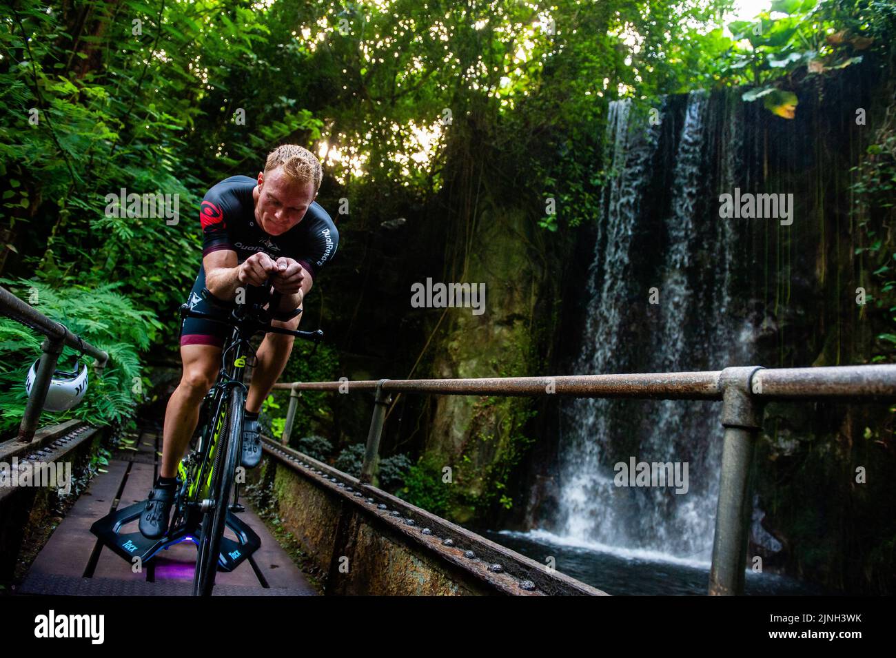 Arnhem, Niederlande. 11. August 2022. Blick auf den Wasserfall mit Athlet Olaf Van Den Bergh beim Training auf seinem Fahrrad. Der niederländische Spitzensportler Olaf Van Den Bergh beginnt im tropischen Regenwald des Burgers' Zoo in Arnhem zu trainieren, um sich auf die Ironman-Weltmeisterschaft in Kailua-Kona in Hawaii vorzubereiten. Der Bush (Indoor Tropical Rainforest) ist aufgrund der hohen Luftfeuchtigkeit und Temperatur der ideale Trainingsort. (Foto: Ana Fernandez/SOPA Images/Sipa USA) Quelle: SIPA USA/Alamy Live News Stockfoto