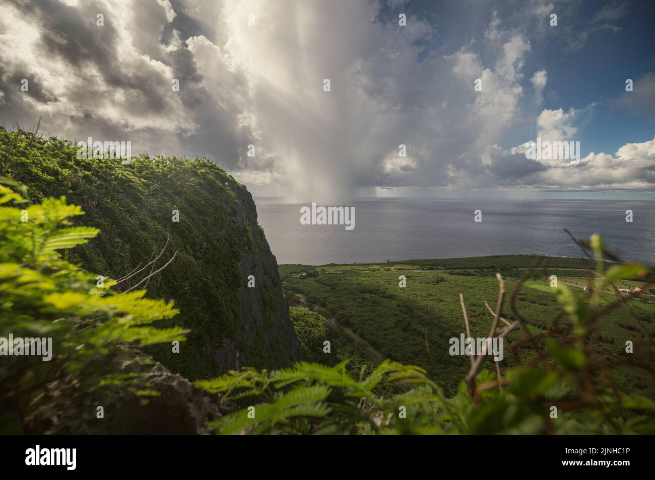 Ein Blick von der Spitze der Suicide Cliffs auf Saipan, während sich eine Regenwolke einzieht. Am 5. August 2022 flog eine Gruppe von Flugzeugern, die dem Lufttankflügel 157. zugewiesen wurden, an Bord eines KC-46 Pegasus nach Saipan im Rahmen einer Super-Sortie-Ausdauerübung. (USA Foto der Air National Guard von Staff Sgt. Timothy Hayden). Stockfoto