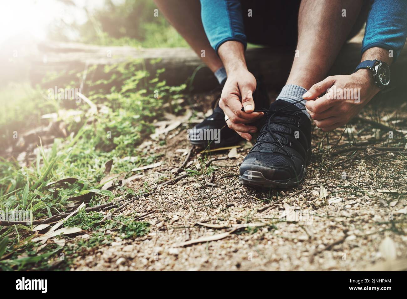 Bereit für den nächsten großen Schritt nach vorne. Nahaufnahme eines nicht erkennbaren Mannes, der seine Schnürsenkel auf einem Wanderweg festschnürt. Stockfoto