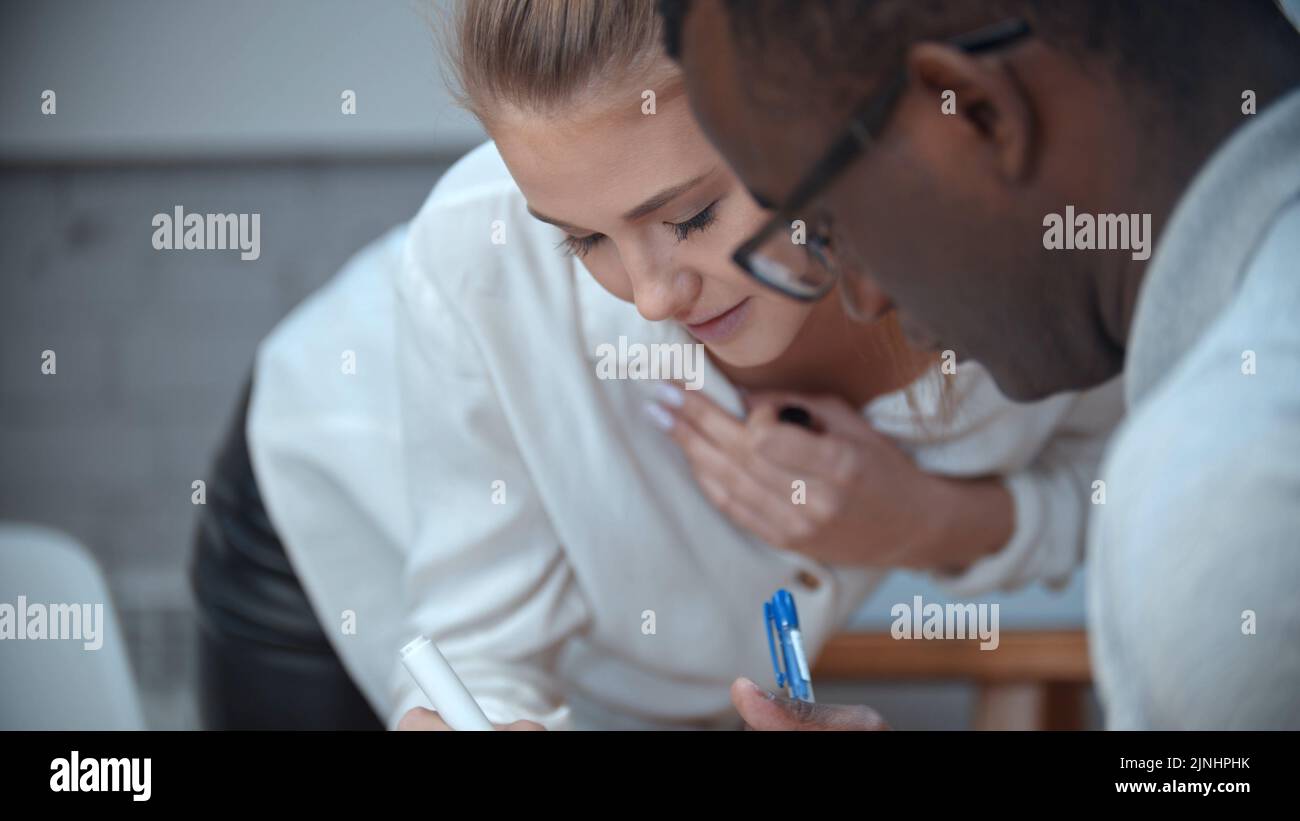 Eine Frau beugt sich vor ihrem schwarzen männlichen Kollegen Stockfoto