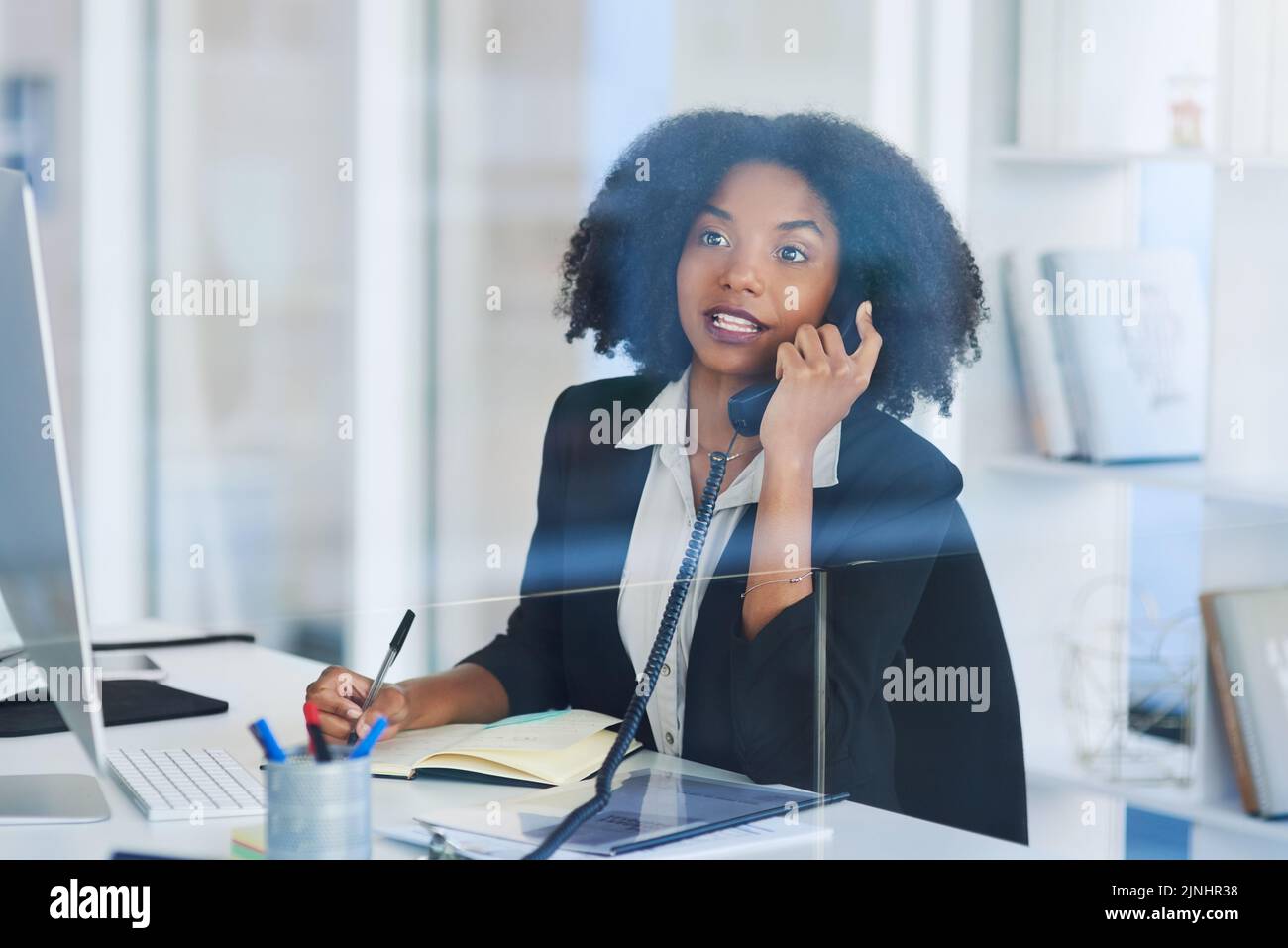 Ich rufe nur an, um mich nach etwas zu erkundigen... eine junge Geschäftsfrau, die in einem Büro am Telefon spricht. Stockfoto