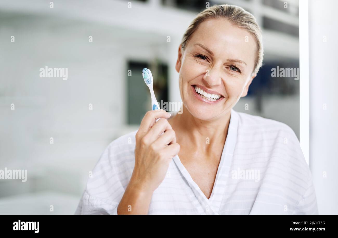 Es gibt nur eine Aufhellungstechnik, an die ich glaube: Eine reife Frau, die mit einer Zahnbürste posiert. Stockfoto