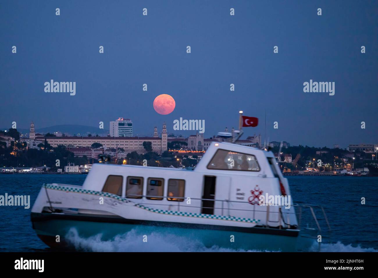 Istanbul, Türkei. 11. August 2022. Als der Vollmond über den Selimiye Barracks in Istanbul auftauchte, sah ein Seetaxi am Bosporus eine Kreuzfahrt. Boote, die durch den Bosporus und die Stadtlinien-Fähren fuhren, wurden in Istanbul gesehen, wobei der Vollmond am Himmel in den Abendstunden erschien. Kredit: SOPA Images Limited/Alamy Live Nachrichten Stockfoto