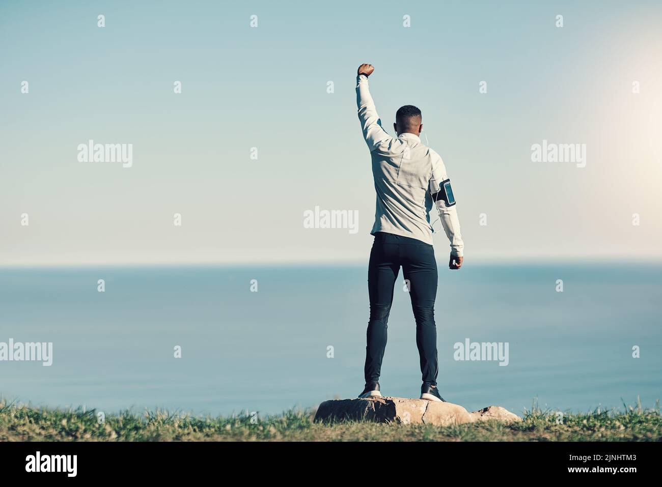 HES hat alles erobert. Rückansicht eines nicht erkennbaren jungen Mannes, der mit erhobener Hand im Freien trainieren konnte. Stockfoto