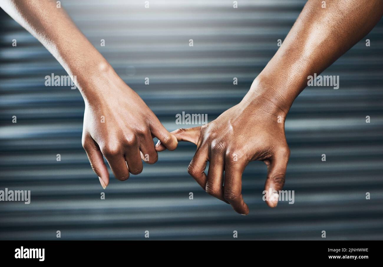 Versprechen Sie, dass Sie hart daran arbeiten können. Nahaufnahme eines sportlichen Paares, das sich mit einem kleinen Finger vor einem grauen Hintergrund hält. Stockfoto