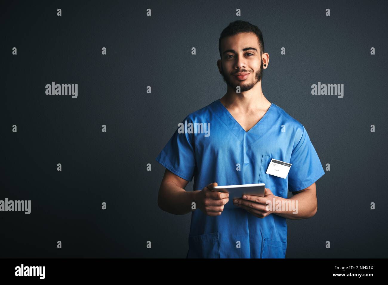 Ich diagnostiziere digital. Studioaufnahme eines jungen Arztes mit einem digitalen Tablet vor grauem Hintergrund. Stockfoto