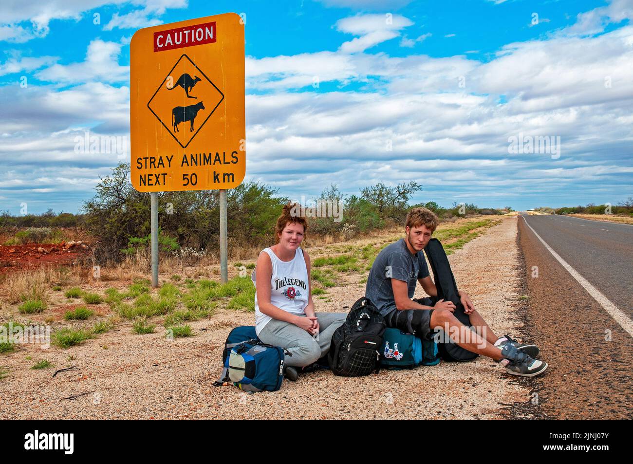 Ein paar junge britische Rucksacktouristen warten auf einen Aufzug auf der Autobahn in der Nähe von Monkey Mia in Westaustralien Stockfoto