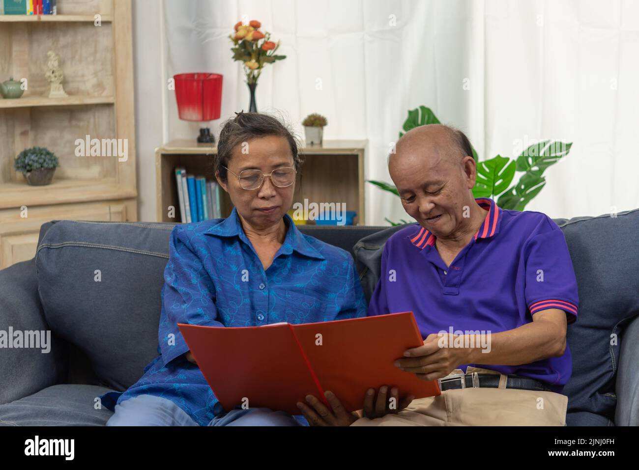 Senior Asian paar reden glücklich planen Rentenversicherung Krankenversicherung Vertrag auf Sofa. Stockfoto