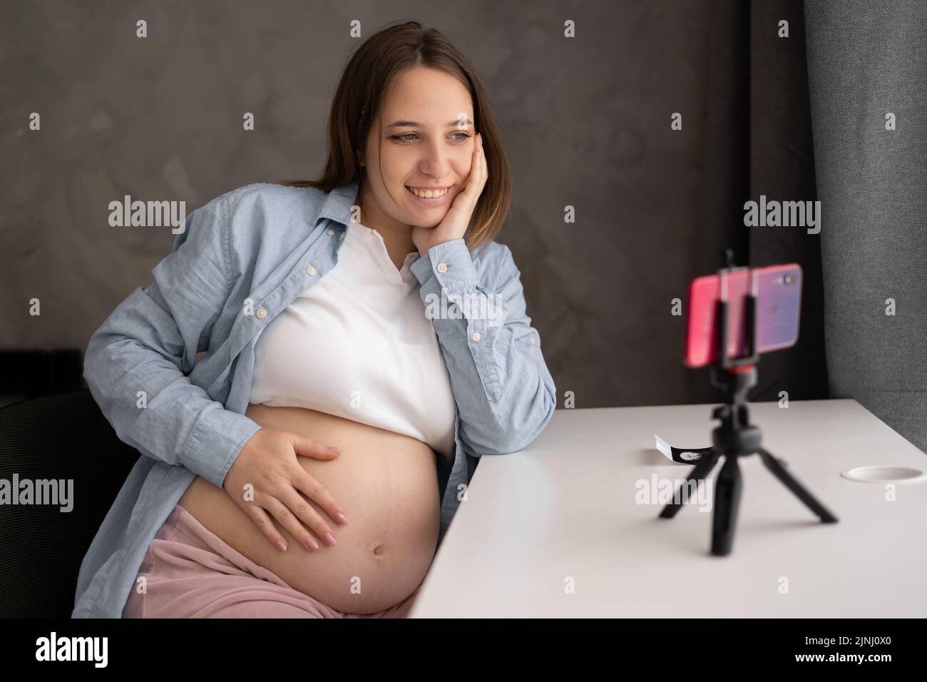 Junge hübsche schwanger Mädchen zu Hause zeichnet Videos auf ihrem Smartphone. Schwanger kaukasische Bloggerin Streaming-Video auf Social Media. Mutter wird erwartet Stockfoto