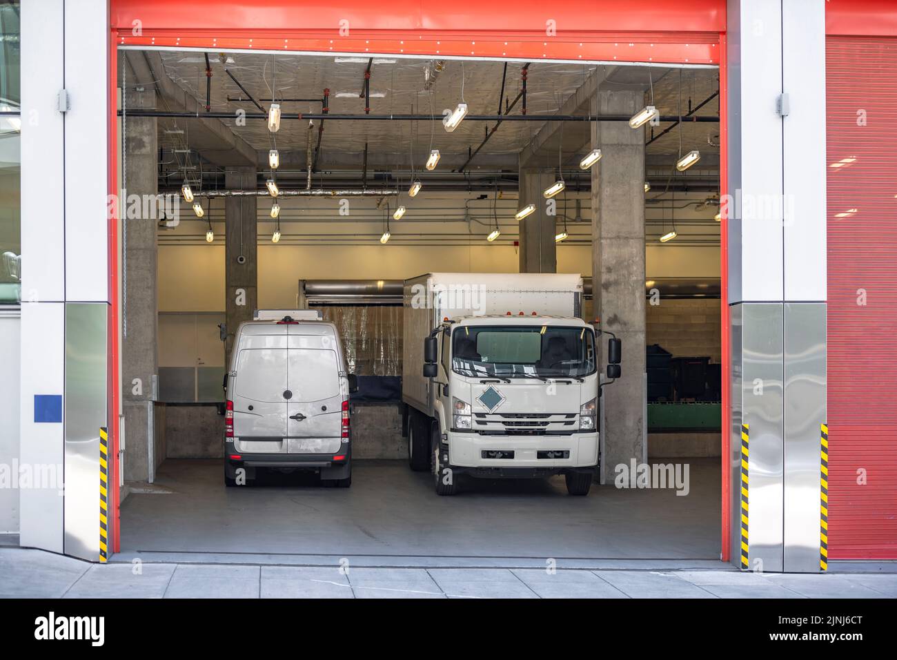 Industriestandard für lokale Lieferungen und Kurzstreckenfrachten Kleintransporter und Kleintransporter mit Boxanhänger, der Waren im Gebäude g ablädt Stockfoto