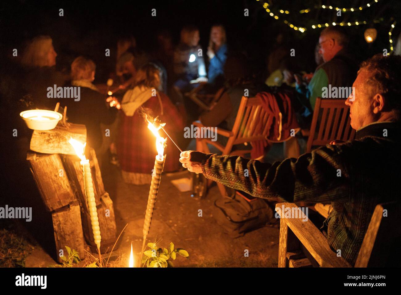 Ein Partygänger schmilzt während einer späten Party in East Sussex am 6.. August 2022 in Horns Cross, England, eine Marschall über den Flammen eines Feuers. Stockfoto