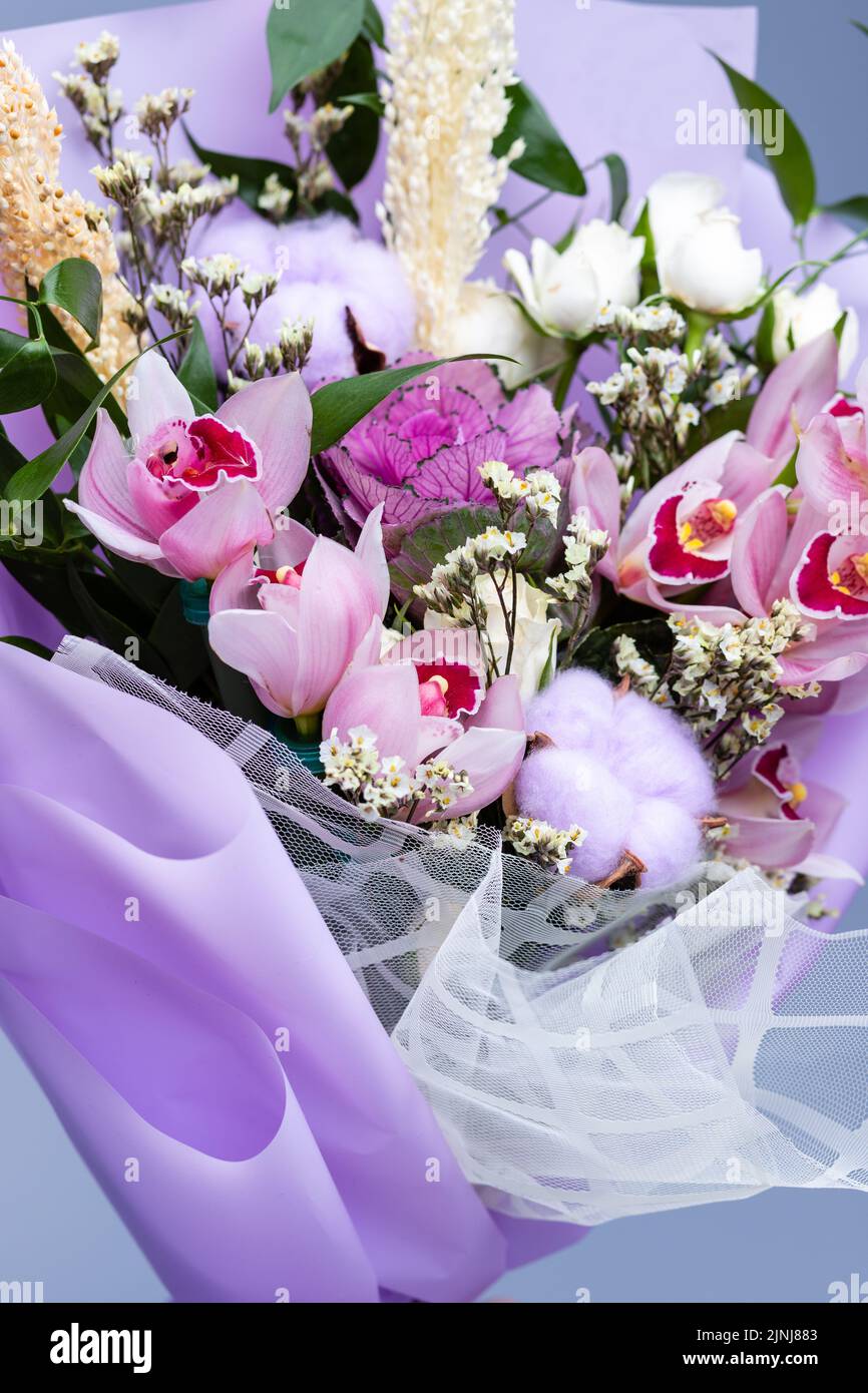 Nahaufnahme eines Blumenstraußes mit frischen natürlichen Zutaten, eingewickelt in florales Pauspapier. Festlich verpacktes Bouquet im rosa Stil, bestehend aus Iris, Stockfoto