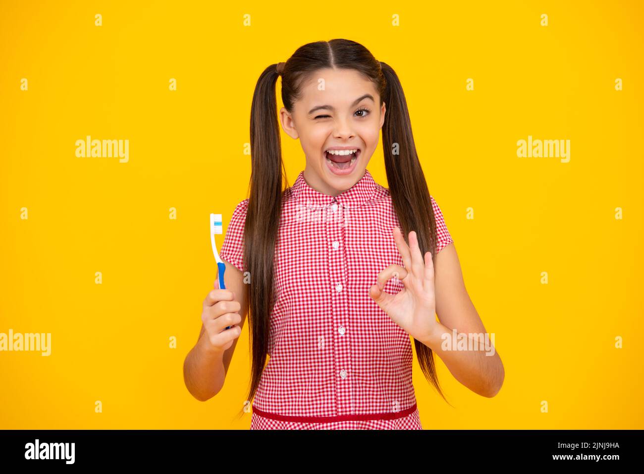 Ein erstaunlicher Teenager. Teenager-Mädchen putzt ihre Zähne über isolierten gelben Hintergrund. Tägliche Hygiene Teenager Kind halten Zahnbürste, morgendliche Routine. Zahnmedizin Stockfoto