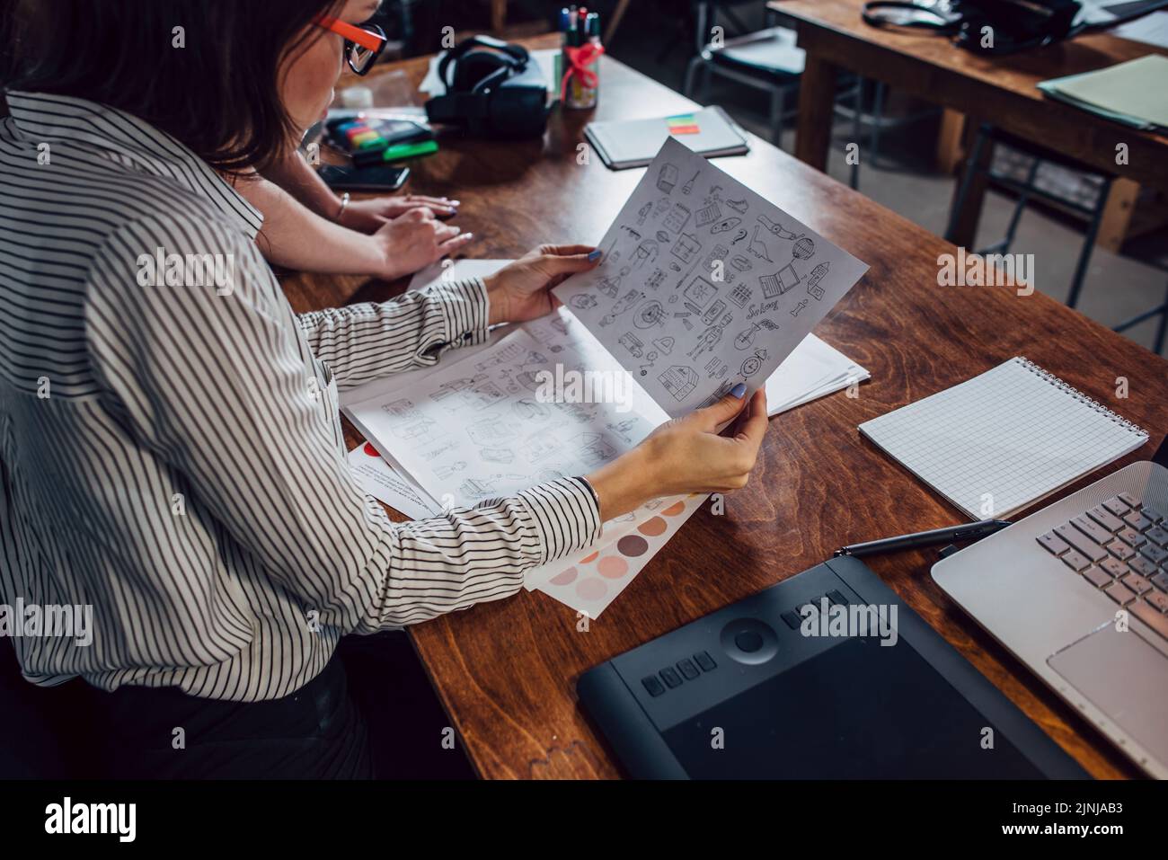 Kreatives Team von Grafikdesignern, die an einem neuen Projekt mit Farbfeldern und Skizzen von Website-Elementen arbeiten. Stockfoto