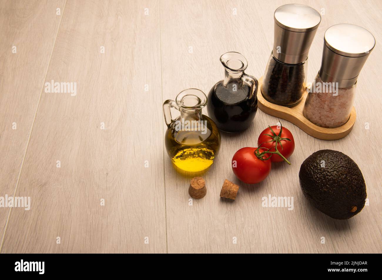 Zutaten für Tomaten- und Avocado-Salat bereit für die Zubereitung auf einer hellen Holzoberfläche mit Platz für Kopien Stockfoto