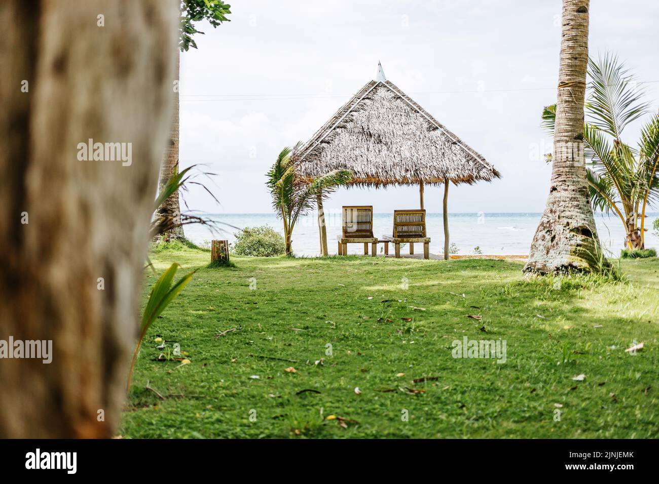 Ein Reetdach mit zwei Strandliegen in Romblon, Philippinen Stockfoto