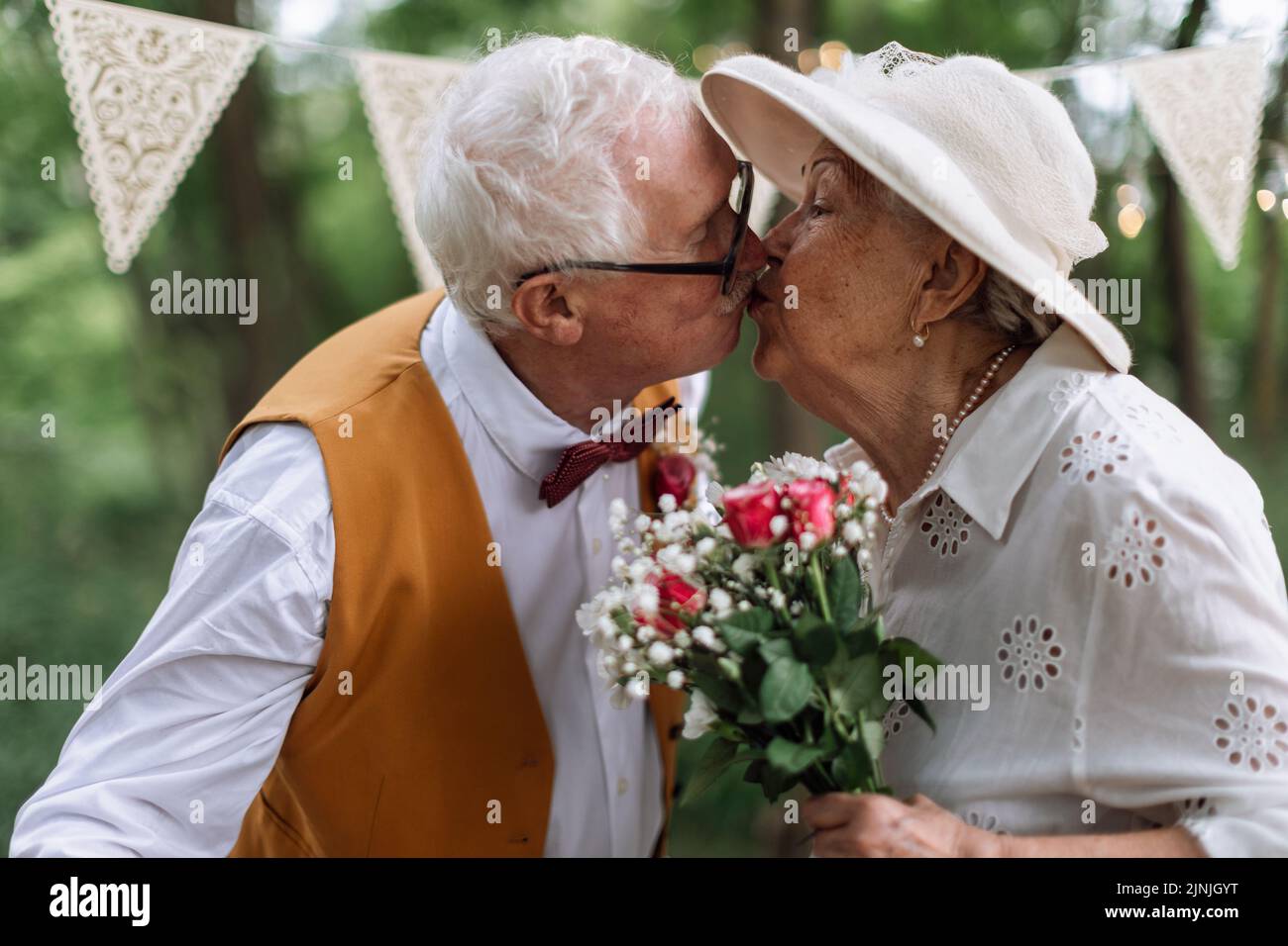 Seniorenpaar, das geheiratet hat und sich während des Sommers in der Natur küsst. Stockfoto
