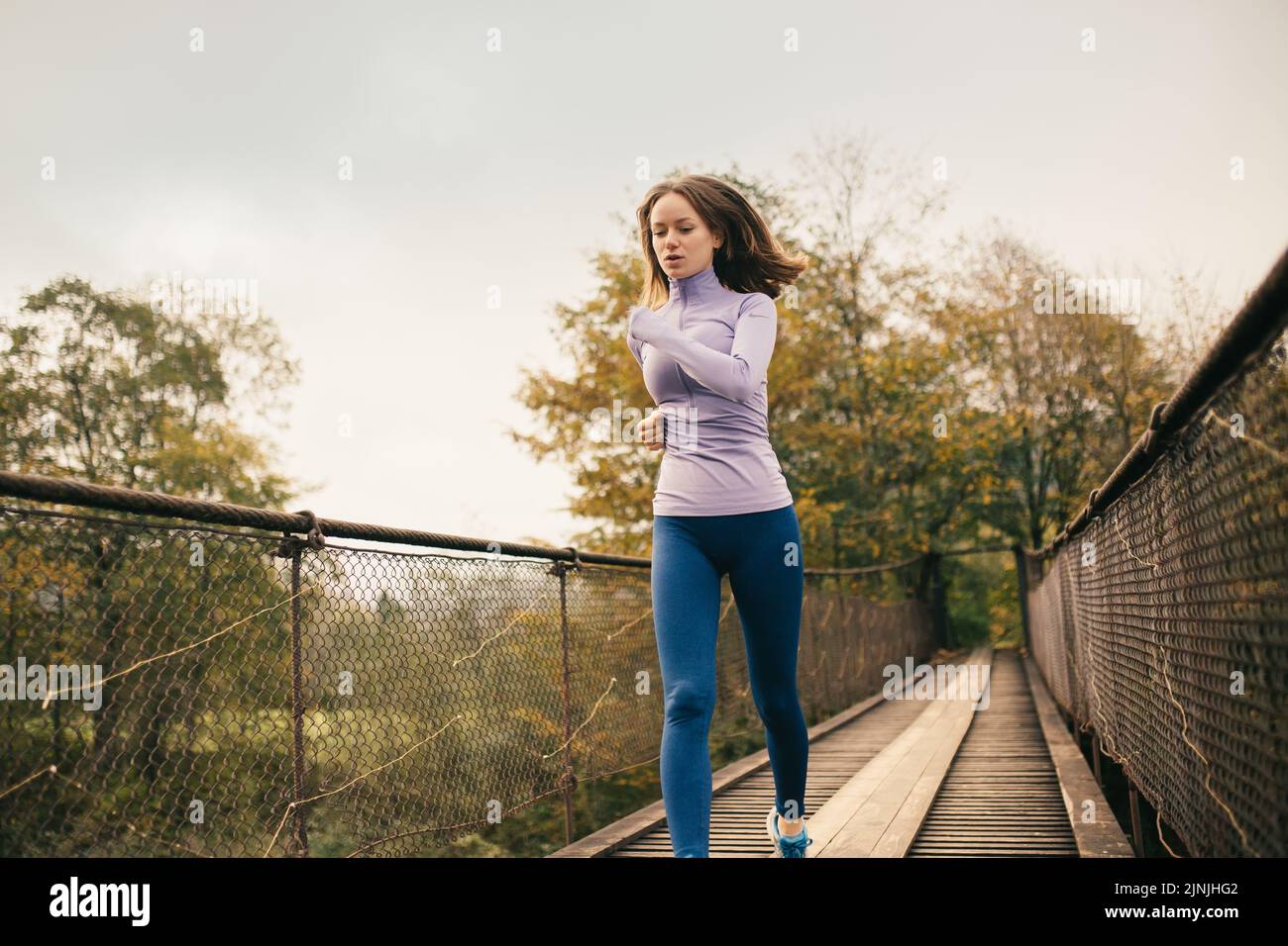 Ein gesunder Lebensstil. Junge sportliche Frau, die bei Cardio-Übungen über eine Hängebrücke läuft. Weibliche Fitnessathletin beim Joggen Stockfoto