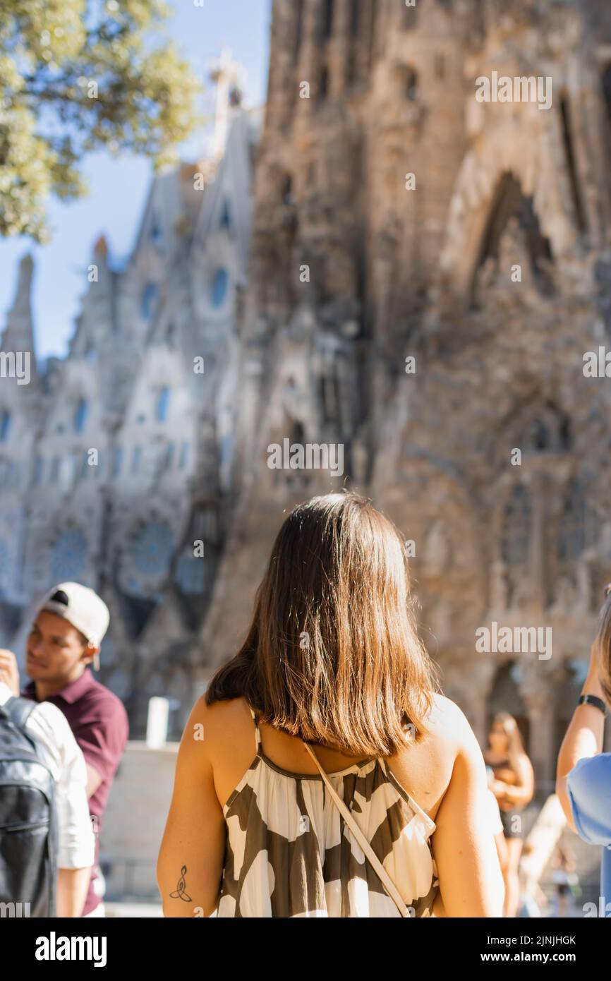 Barcelona, Spanien - 1. Juli 2022: Ein Mädchen auf dem Rücken im Urlaub vor der Sagrada Familia in Barcelona (Spanien). Stockfoto