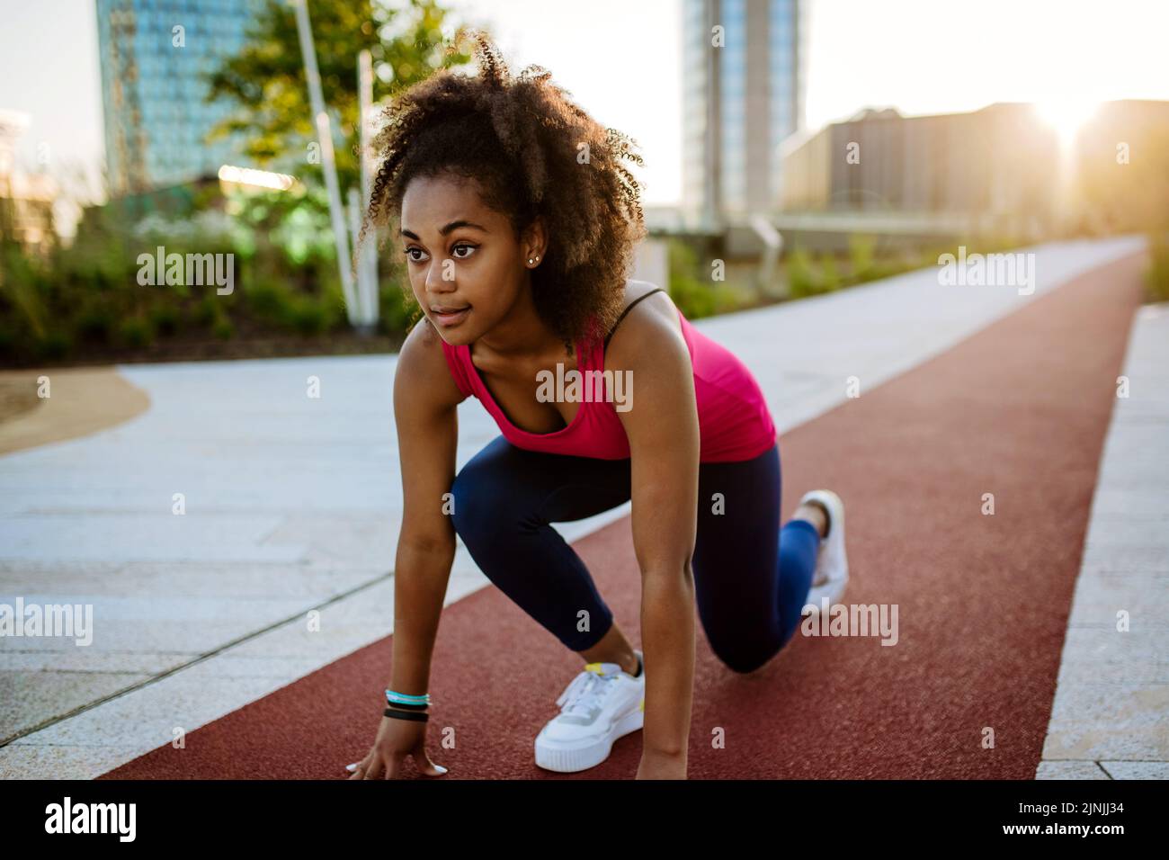 Junge multirassische Mädchen in Sportkleidung Vorbereitung für den Lauf in der Stadt, während des Sommers Sonnenuntergang, goldene Stunde. Stockfoto