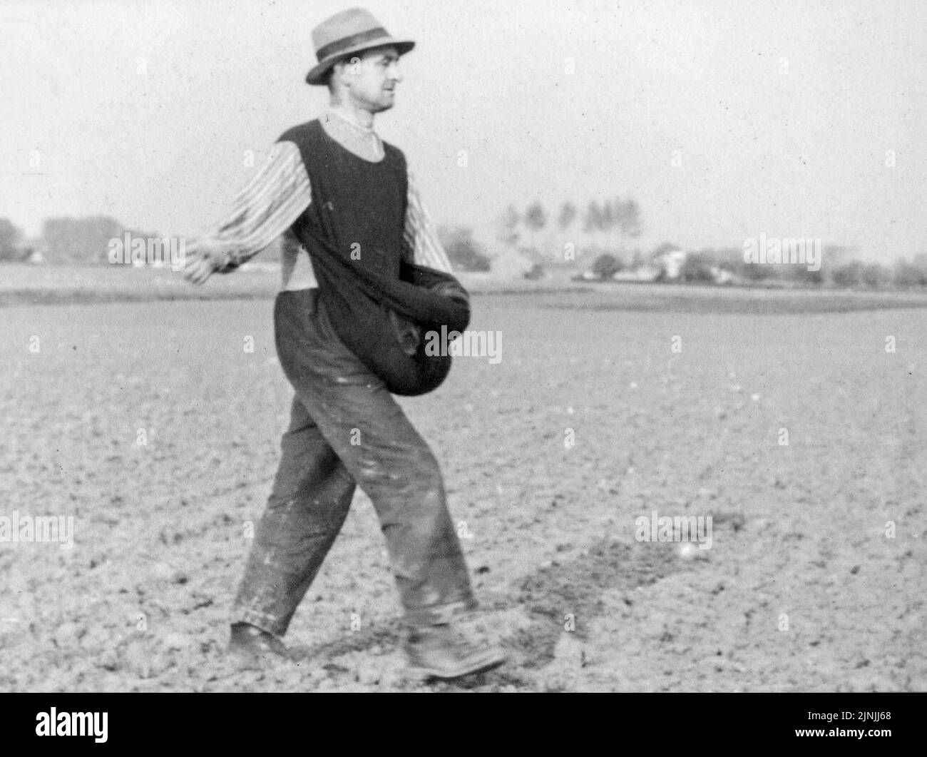 Altes historisches Foto, das Bauern / Landarbeiter / Landarbeiter bei der Aussaat zeigt, indem man Handvoll Samen auf Ackerland wirft Stockfoto