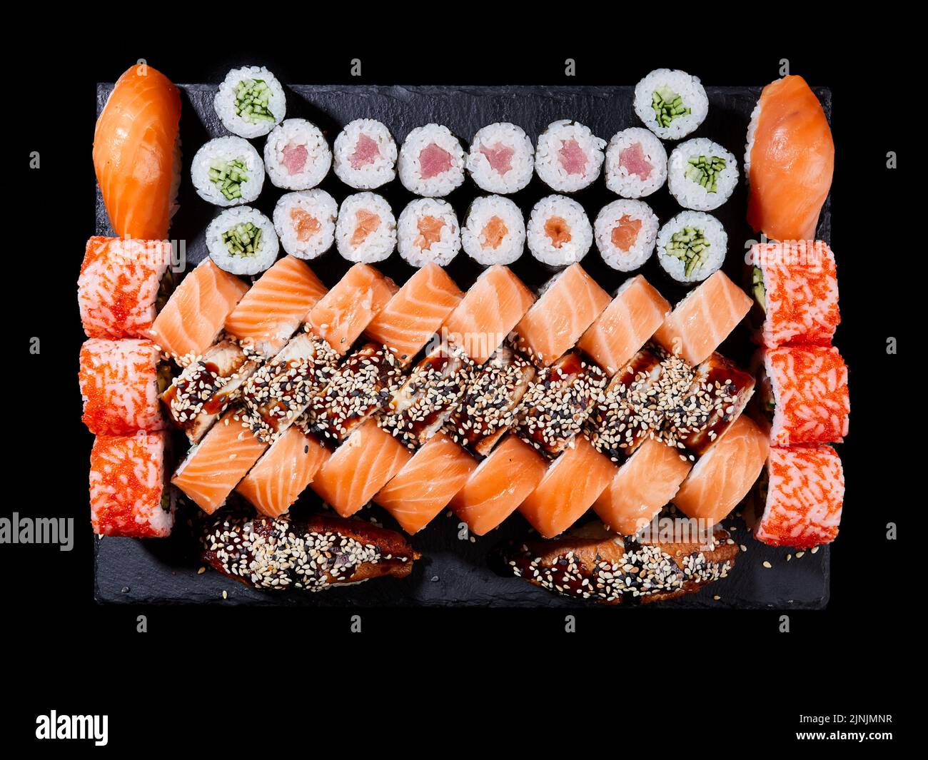 Japanisches Sushi-Essen. Maki und Brötchen mit Thunfisch, Lachs, Garnelen, Krabben und Avocado werden auf Steinschiefer serviert. Draufsicht auf verschiedene Sushi-Sorten. Regenbogen-Sushi Stockfoto