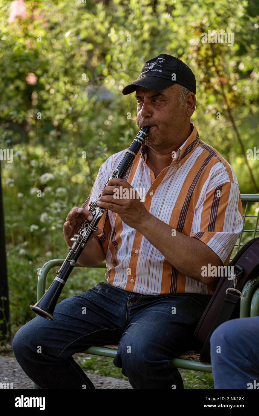 Albanien, 12. Mai 2022 - Albanien, 12. Mai 2022 - Mann spielt Klarinette auf einer Straßenbank zur Spende von Passanten. Stockfoto