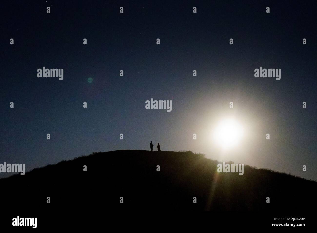Ein Paar beobachtet den Sturgeon-Supermond, den letzten Supermond des Jahres, von einem Hügel in Ealing, West-London. Bilddatum: Donnerstag, 11. August 2022. Stockfoto