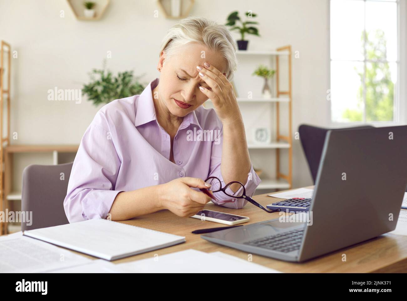 Reife Frau, die sich müde fühlt und Kopfschmerzen hat, nachdem sie an ihrem Laptop gearbeitet hat Stockfoto