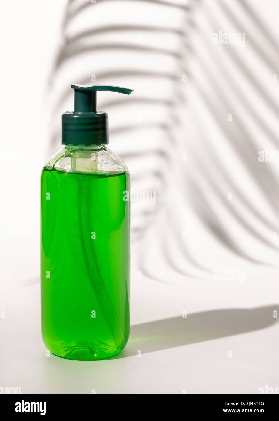Nachfüllbare Kosmetische Pumpe Spender Flasche mit grüner Flüssigkeit auf weiß gefüllt, Palm Blatt harte Schatten, close up, mockup. Hautpflege Beauty-Produkt, Gesichtsbehandlung Stockfoto