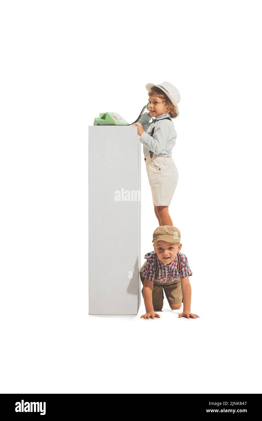 Porträt von zwei fröhlichen Kindern im Retro-Stil Sommer-Outfit mit Vintage-Telefon isoliert auf weißem Hintergrund. Konzept von Kunst, Freundschaft, Hoffnung, Jugend Stockfoto