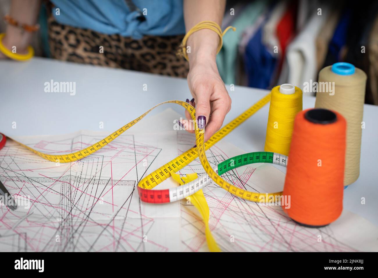 Bunte Fäden auf Spulen stehen auf einem Nähtisch. Schneidermuster. Stockfoto