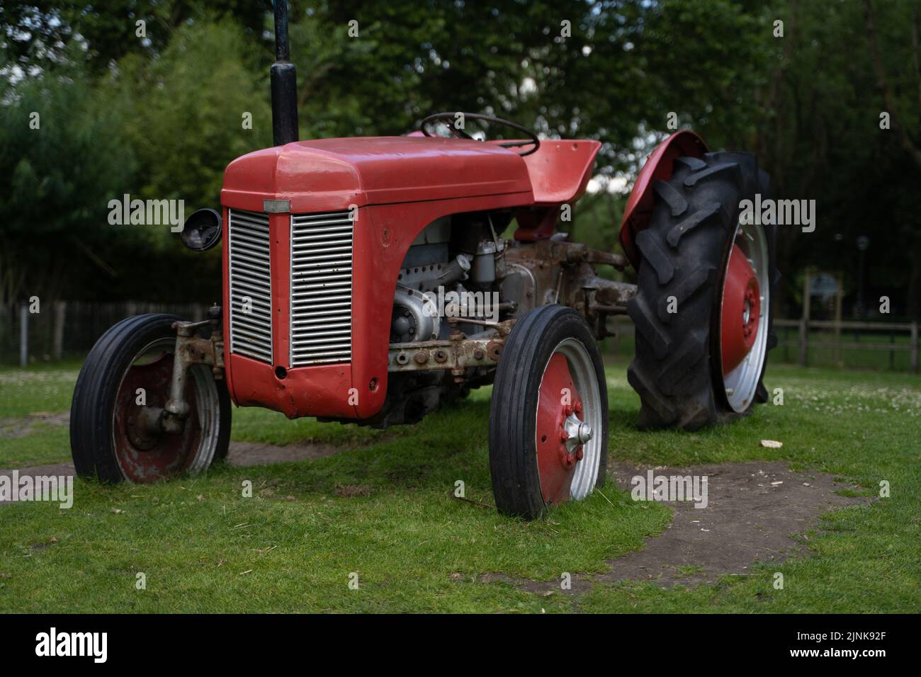Ein alter roter Traktor auf einer grünen Wiese. Stockfoto