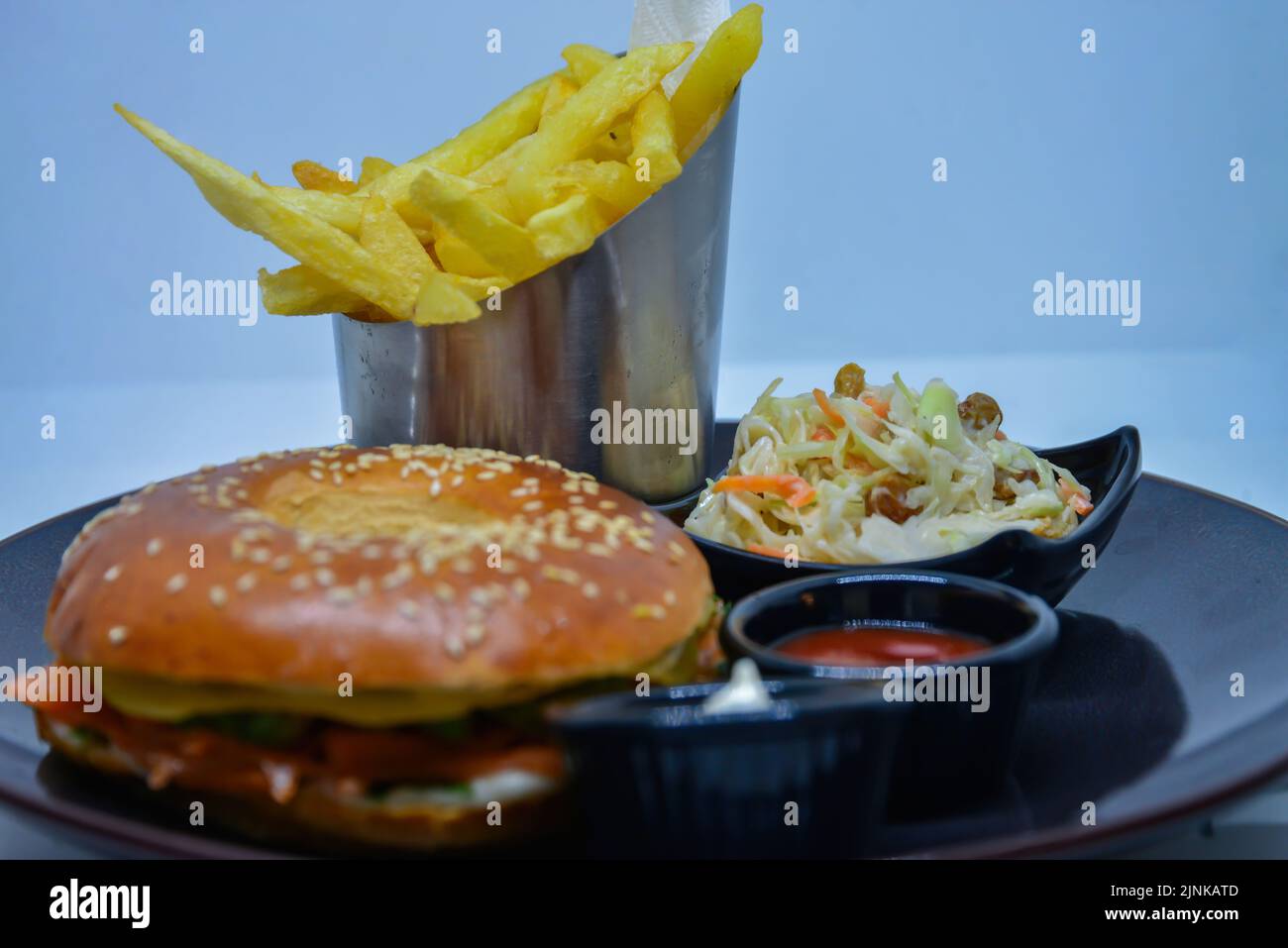 Schnellimbiss. hamburger, pommes Frites und Salat. burger mit Rinderspieß, Käse und Gurke. Ketchup-Senf mit Mayonnaise auf dem Teller. Stockfoto