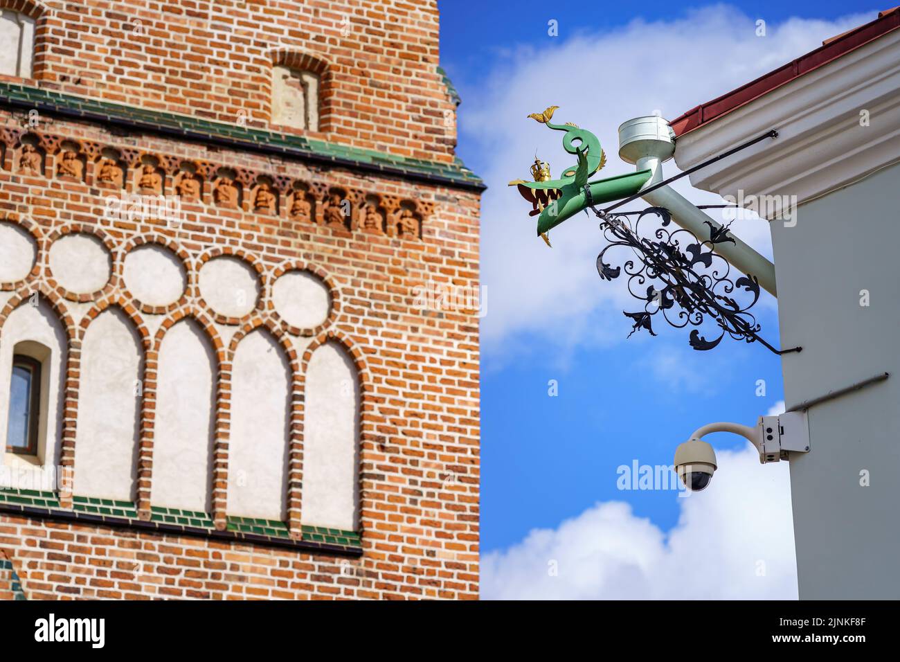 Detail einer mit Drachenfiguren verzierten Rinne und einer Backsteinkirche im Hintergrund. Stockfoto