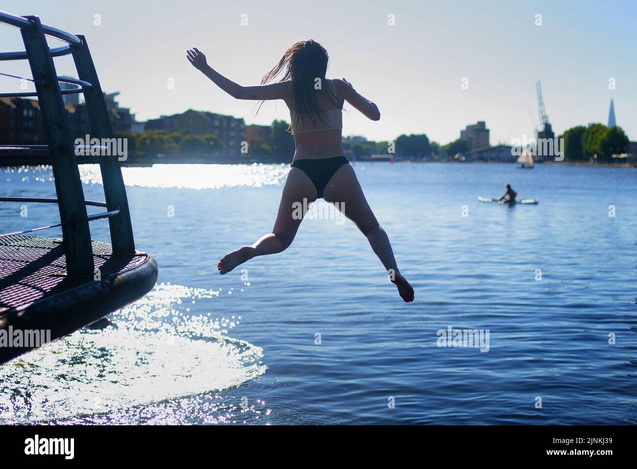 Eine Frau springt auf der Isle of Dogs im Osten Londons ins Wasser. Für einige Teile Englands wird am Freitag eine Dürre ausgerufen, wobei die Temperaturen bis 35C Grad erreichen werden, was das Land heißer macht als Teile der Karibik. Bilddatum: Freitag, 12. August 2022. Stockfoto