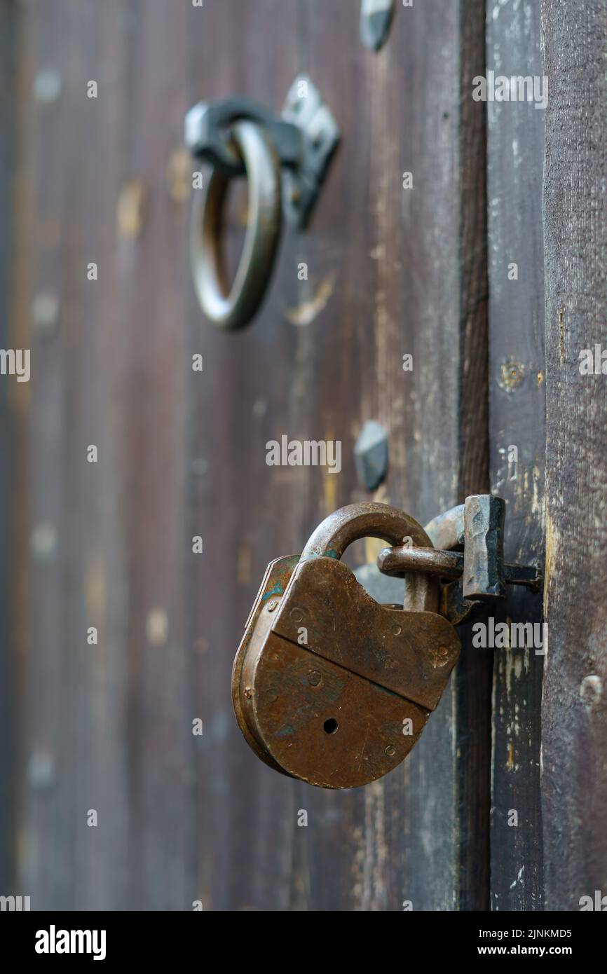 Detail des alten Vorhängeschlosses an der Holztür und des alten Klopfers. Stockfoto