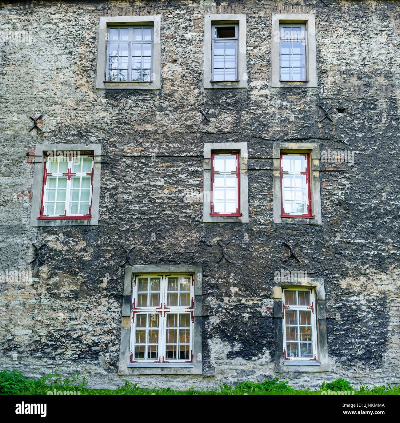 Viele unordentliche Fenster an der sehr alten mittelalterlichen Hausfassade. Stockfoto