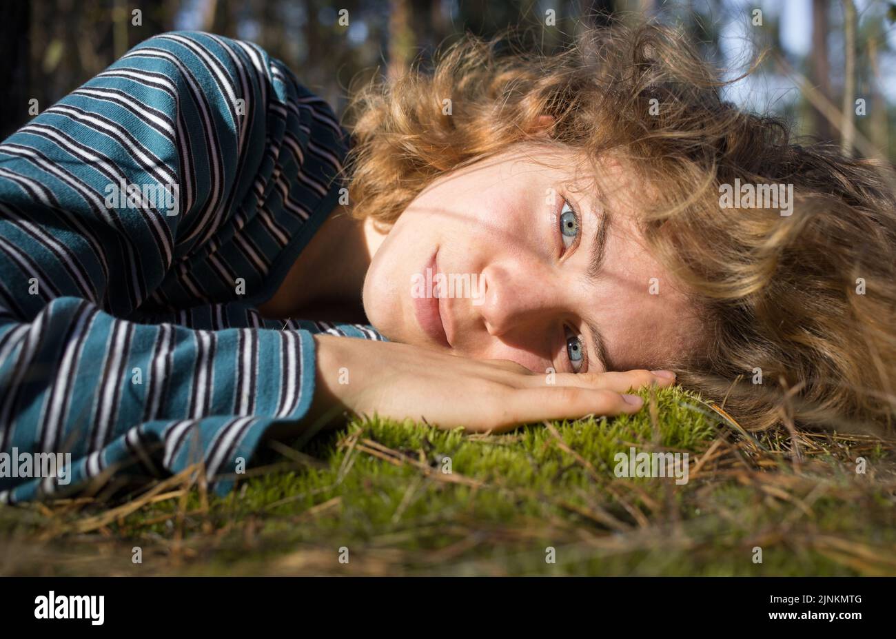 Nettes Teenager-Mädchen liegt auf grünem Moos im Wald genießen einen sonnigen Tag. Outdoor-Erholung, die Lebenskraft der Erde. hallo Frühling, Sommer. Herbst Stockfoto